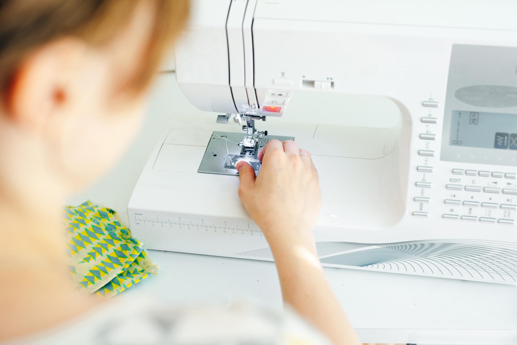 Mano che guida una macchina da ricamo su tessuto tecnico